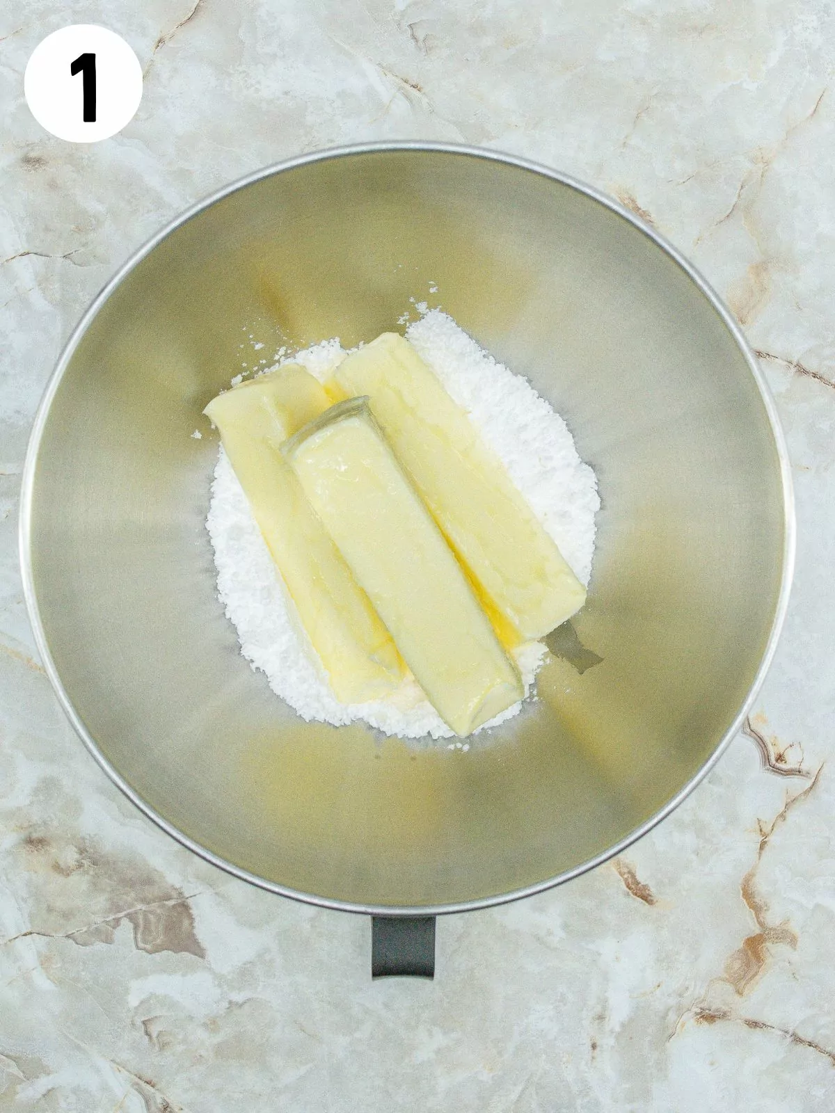 3 sticks of butter in bowl with powdered sugar.