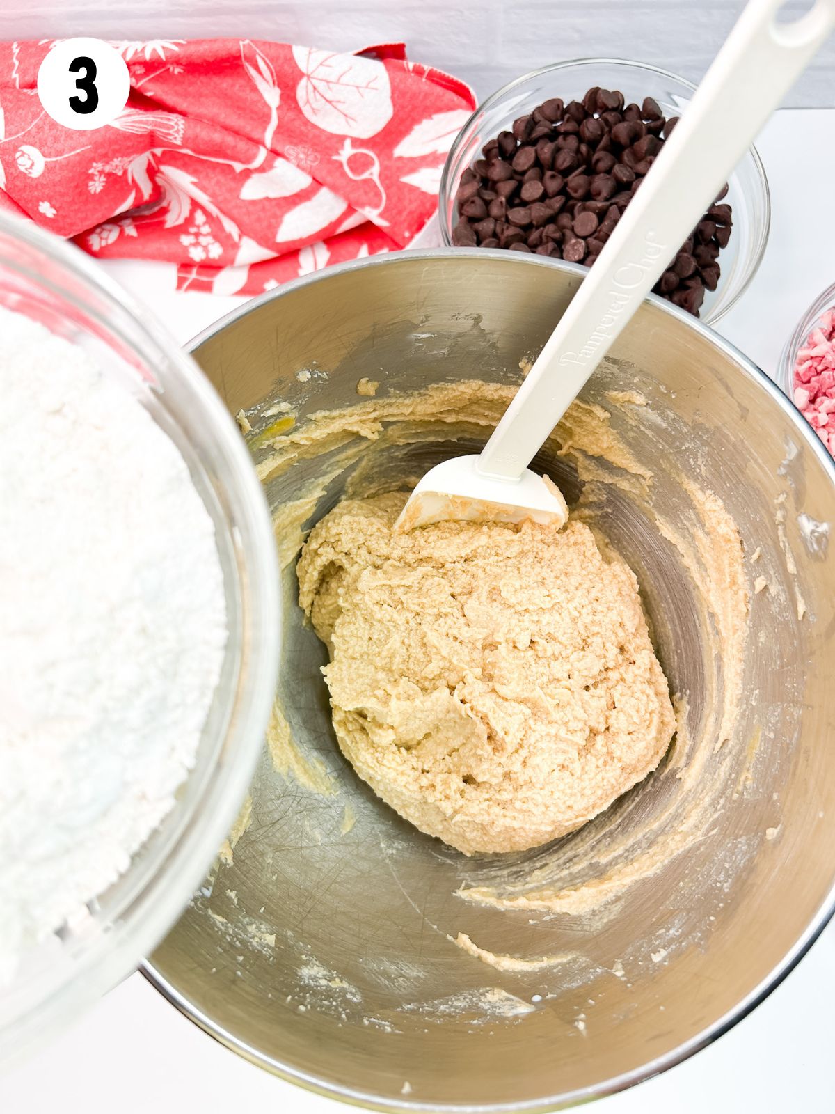 Adding flour to wet ingredients in mixing bowl.