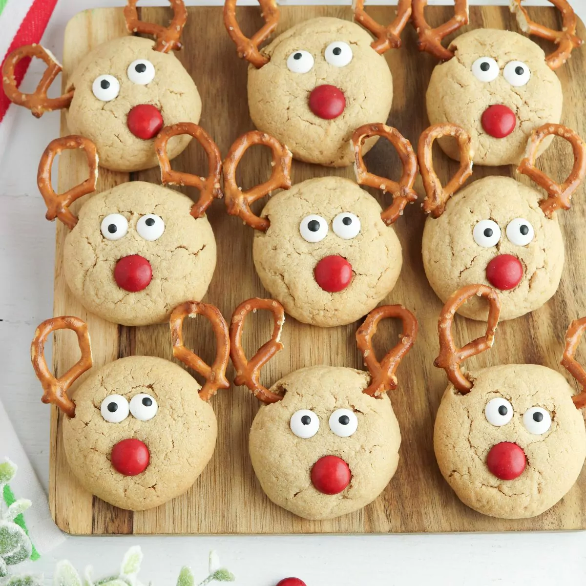 Peanut butter cookies decorated as reindeers with pretzel antlers.