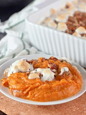 sweet potato casserole with marshmallows and pecans in small white bowl.