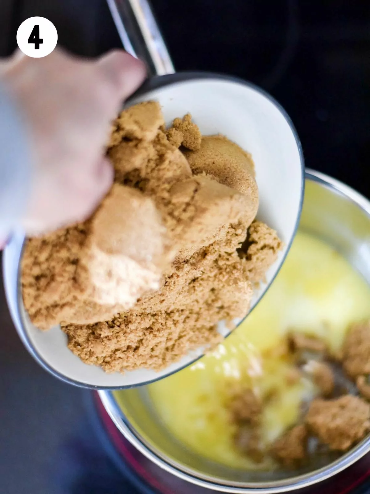Brown sugar in bowl being added to melted butter.