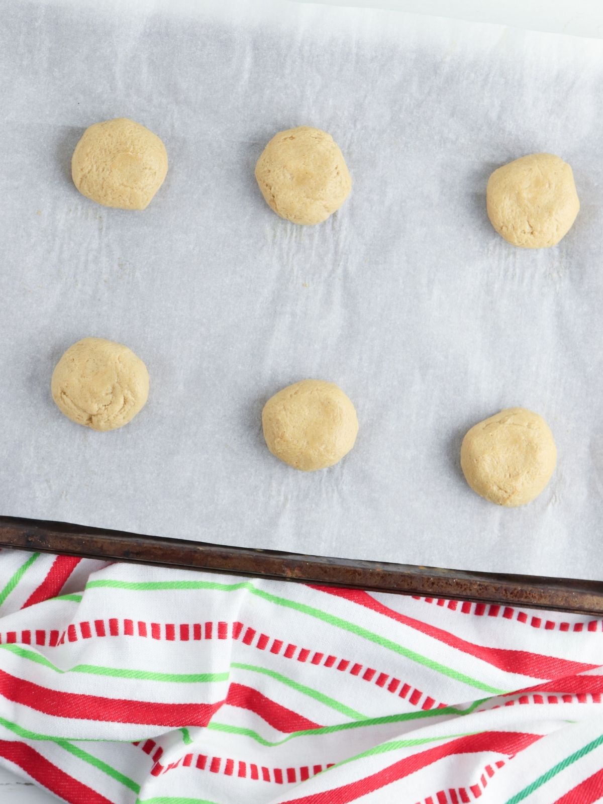 cookie dough balls on baking tray with parchment paper.