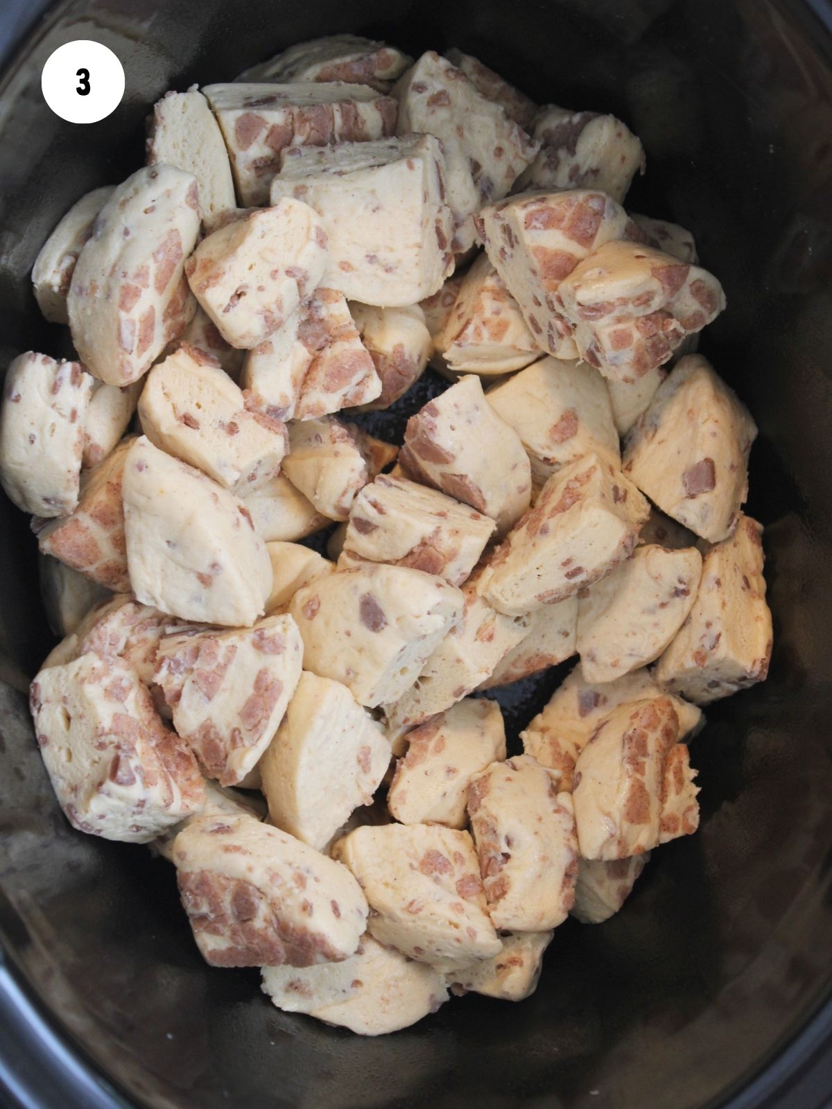 cut up cinnamon rolls in black crock pot.