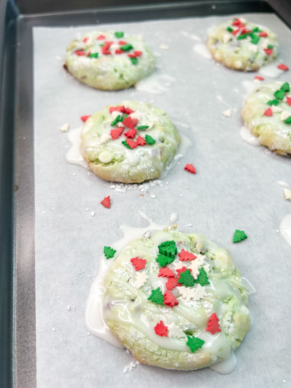 cake mix cookies on baking tray with powdered sugar glaze and sprinkles.