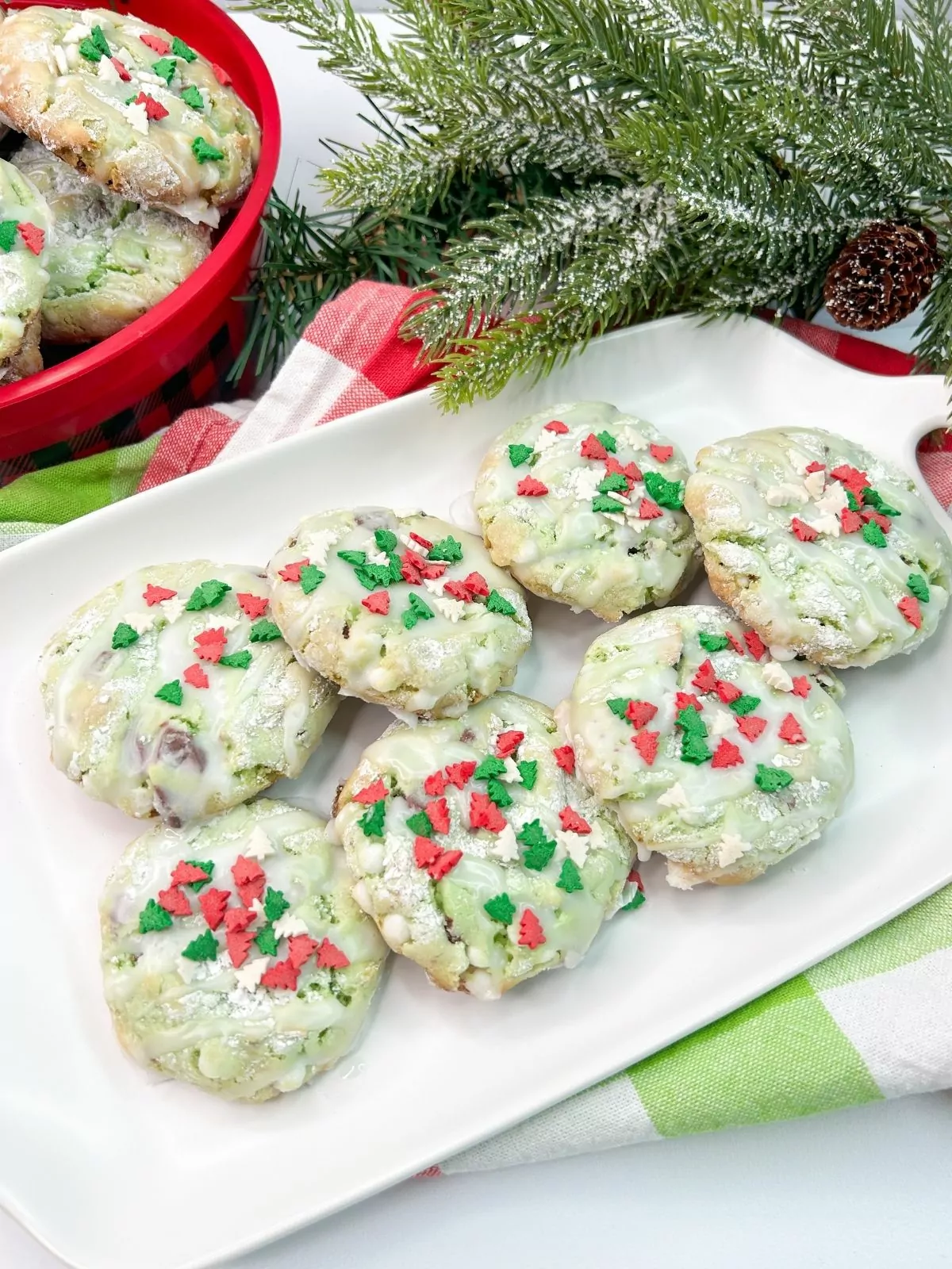 Christmas cookies tinted green with sprinkles on white serving tray.