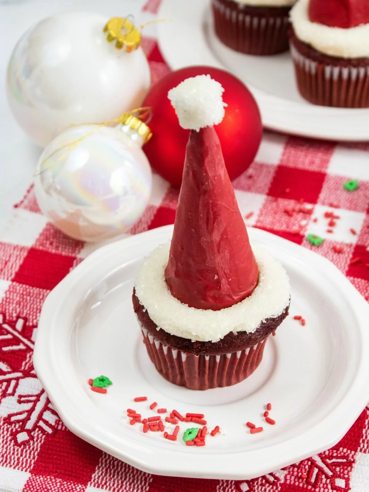 Santa hat cupcake on white plate with red checked placemat underneath.