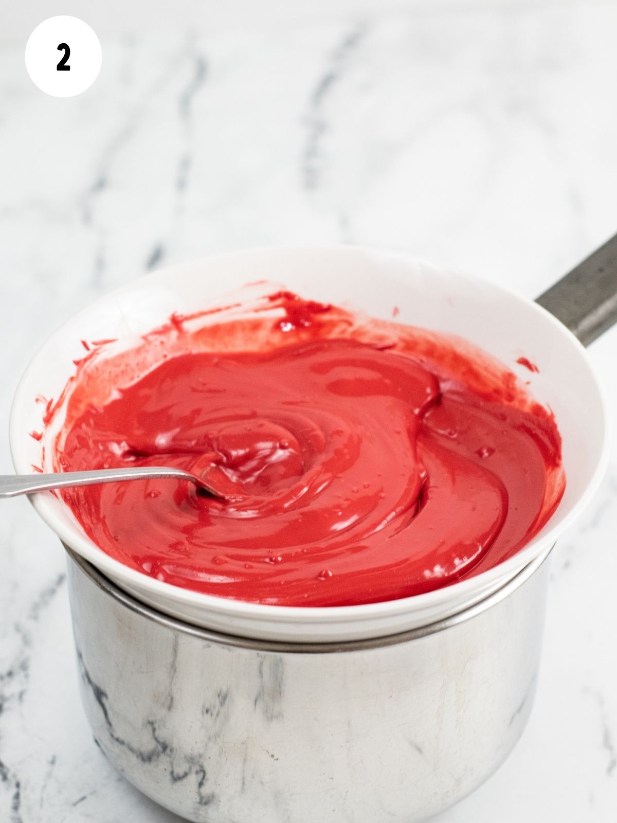 melted red candy melts in bowl on top of saucepan.