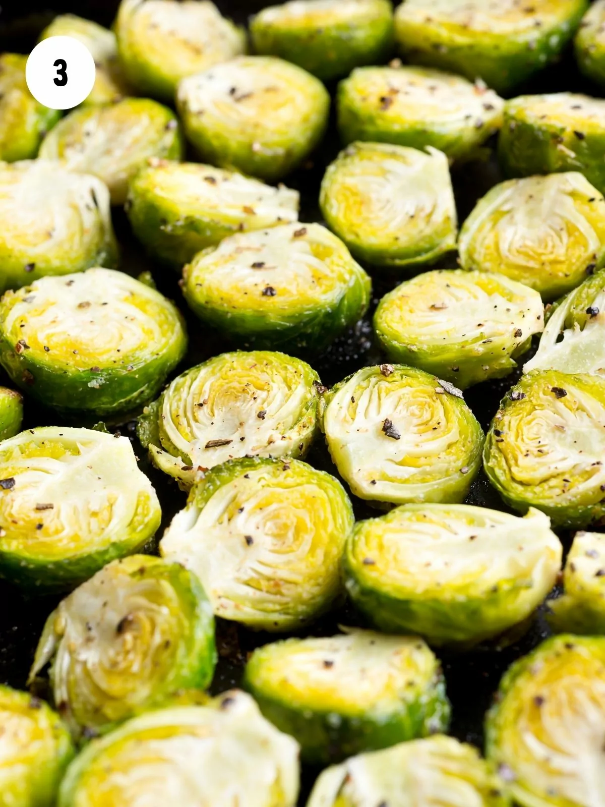 salt and pepper on Brussels sprouts on baking tray with vegetable oil.