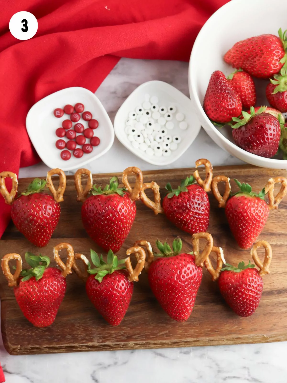 strawberries with pretzel antlers on cutting board.