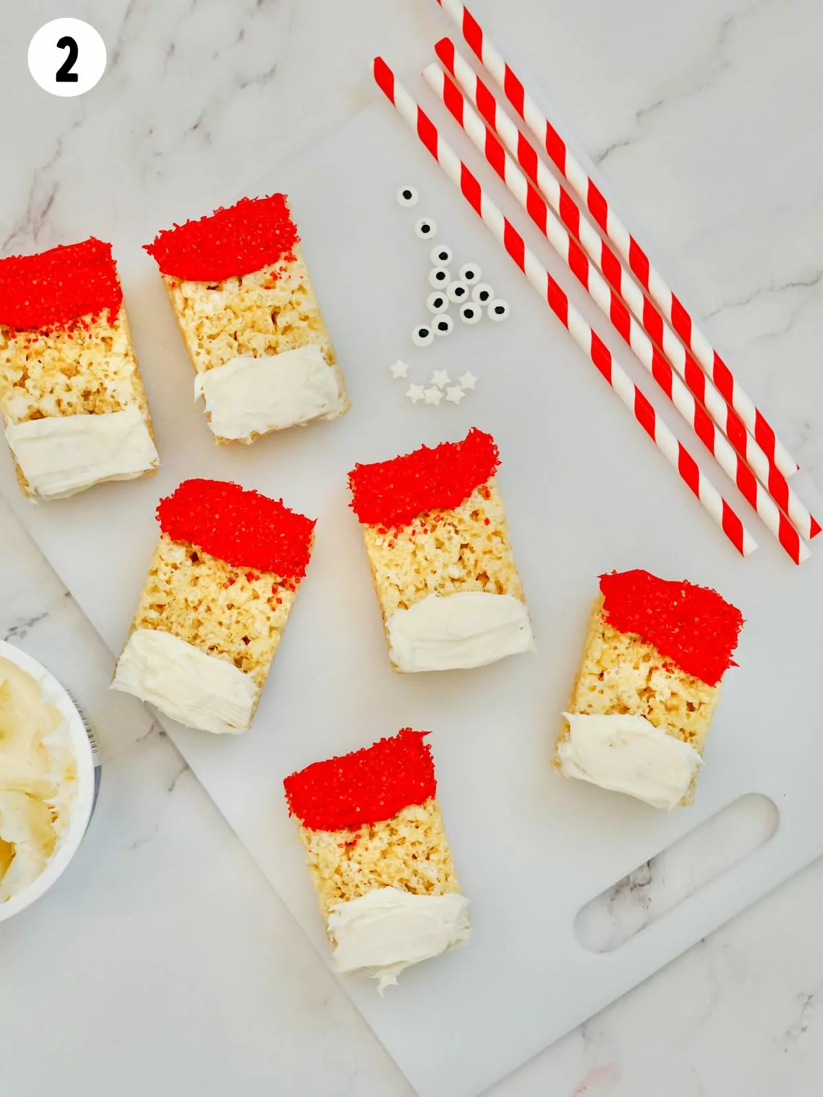 6 rice krispie treats with red and white frosting to look like Santa.