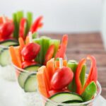 Creamy dip served in individual plastic cups with fresh veggies.