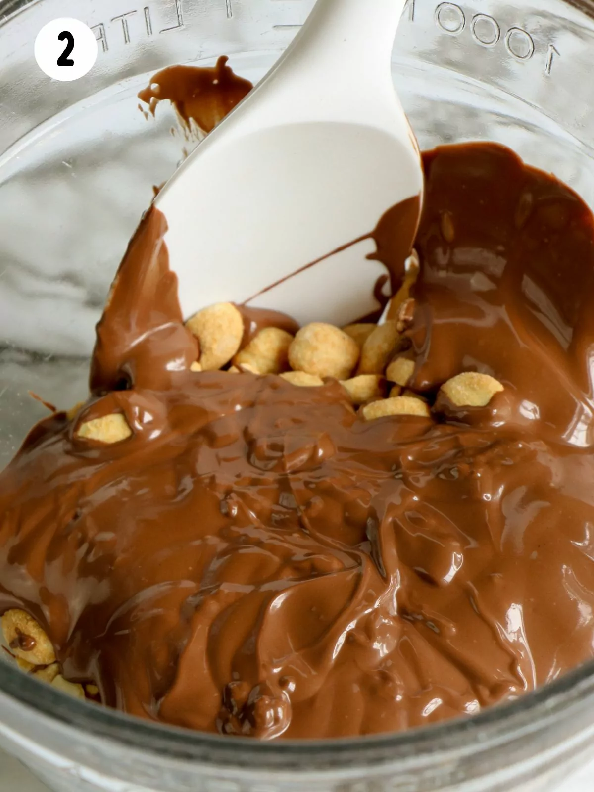 Melted chocolate combined in bowl with peanuts.