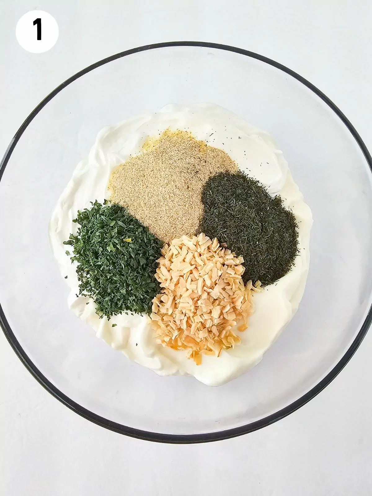 Seasonings on top of sour cream and mayonnaise in bowl.