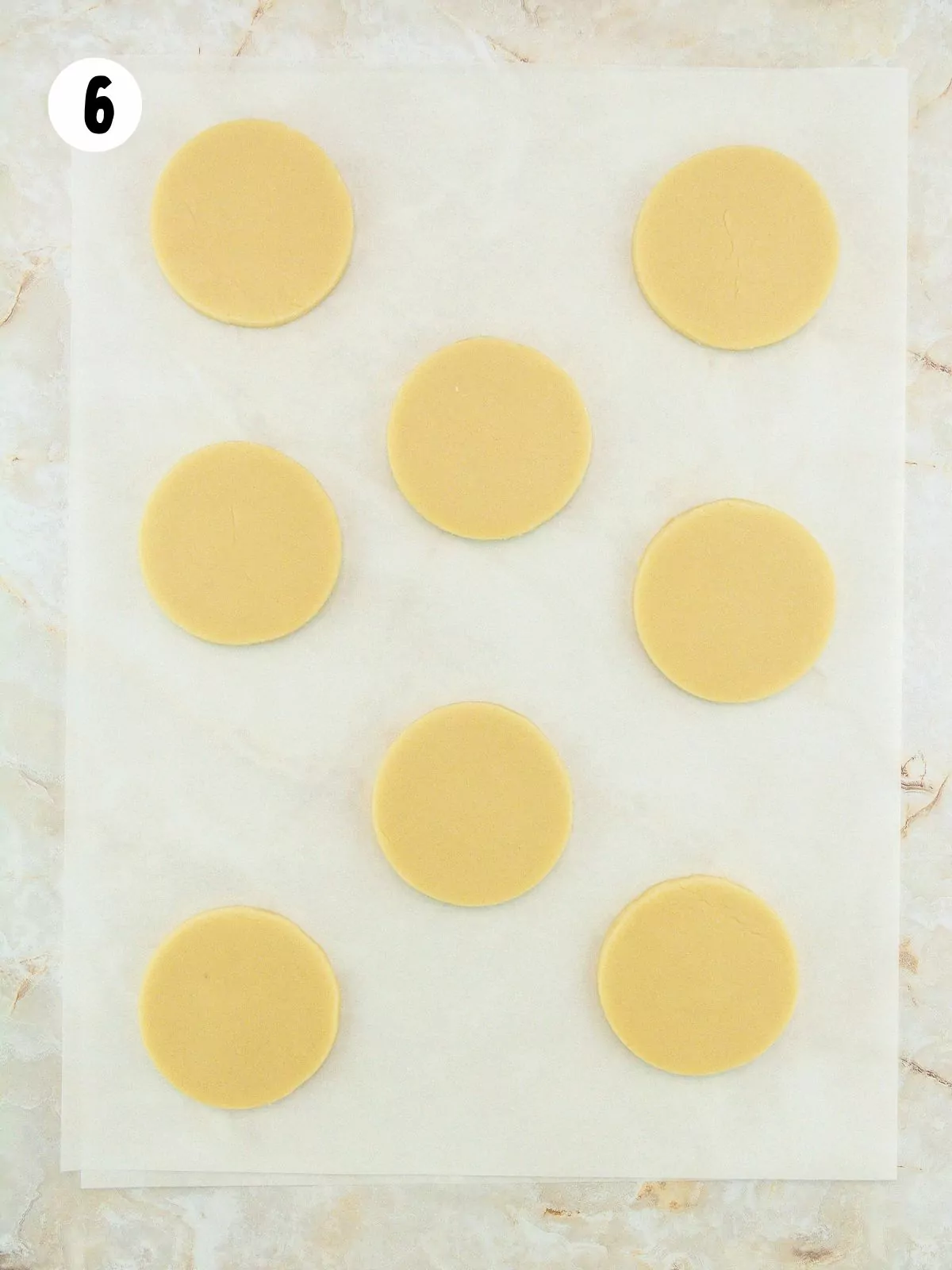 sugar cookie dough rounds on parchment paper.