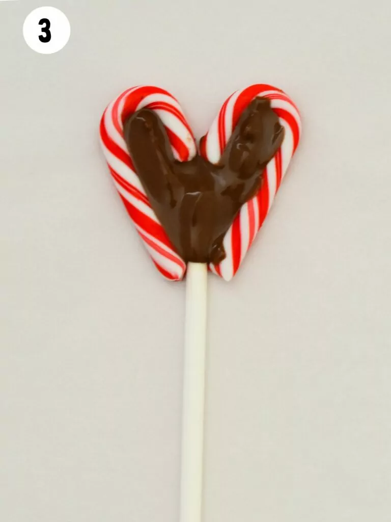 melted chocolate inside candy cane hearts on lollipop stick.