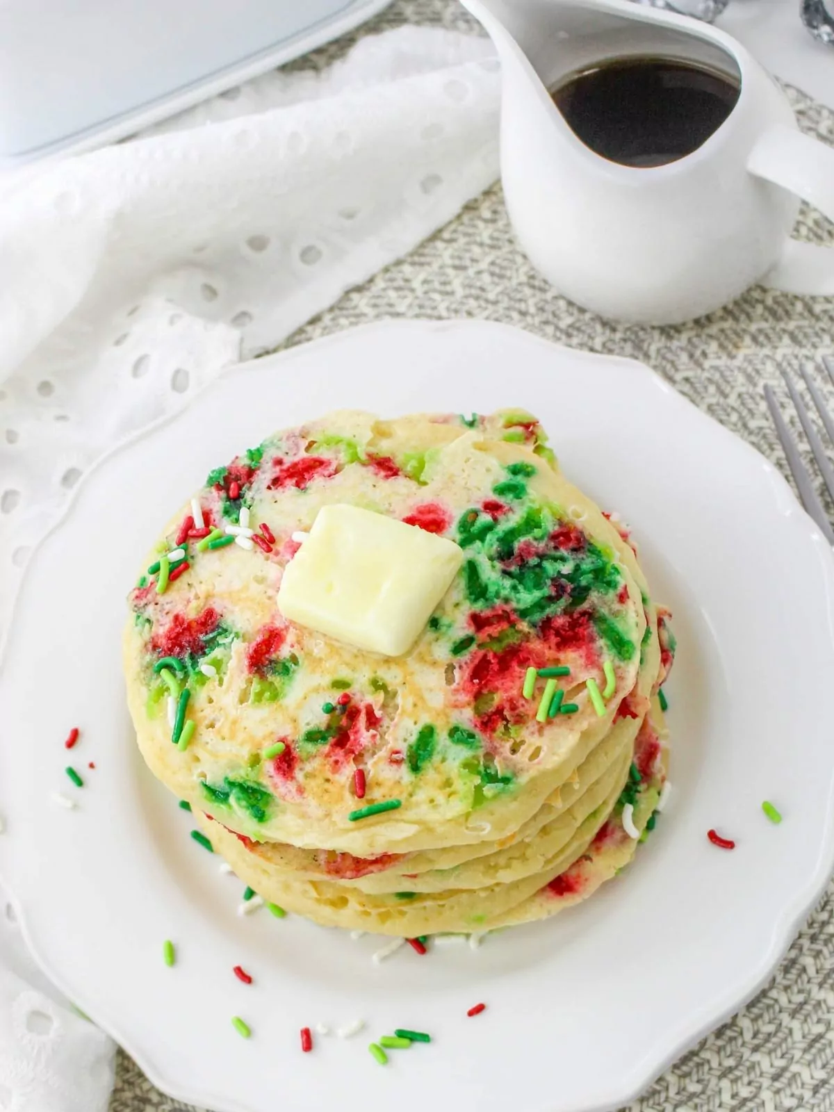 plate of pancakes with sprinkles with a pat of butter on top.