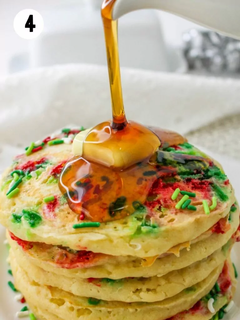 pouring syrup on stack of pancakes with sprinkles.