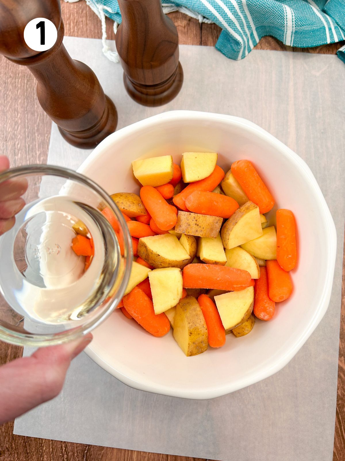 adding vegetable oil to vegetables in white bowl.