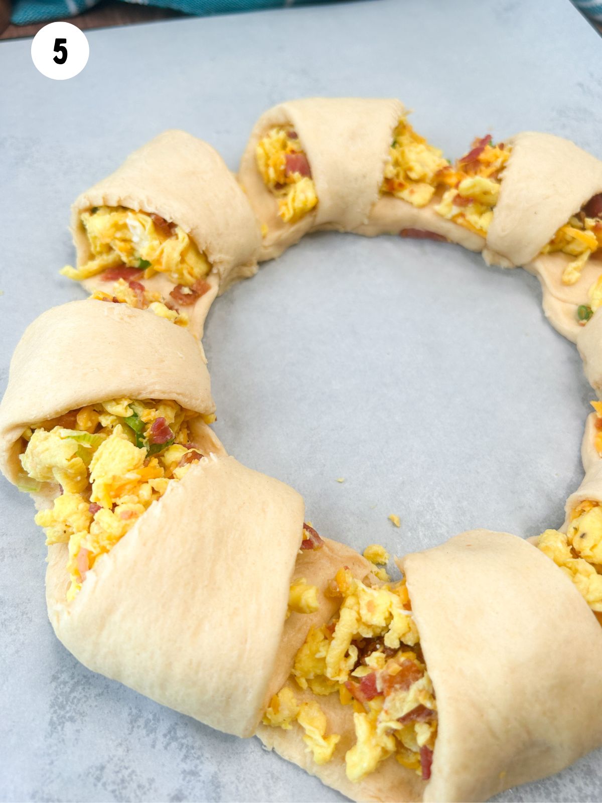 Pre-baked crescent roll breakfast wreath formed and on baking sheet.
