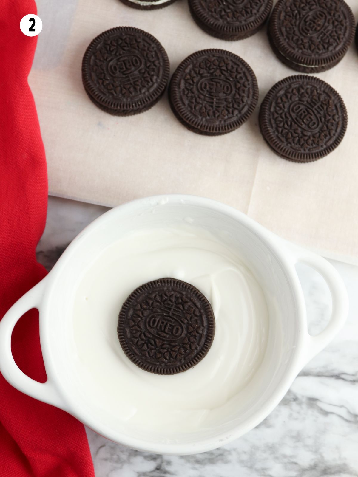 Dipping Oreo cookies in white melted chocolate.