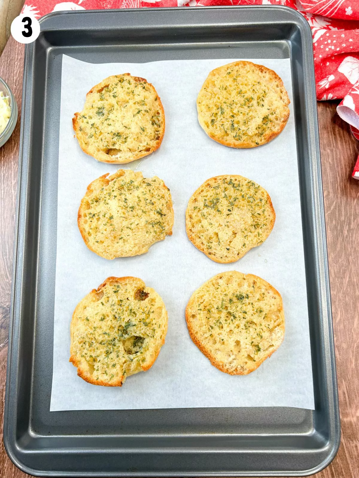 toasted English muffins with homemade garlic butter on baking tray.