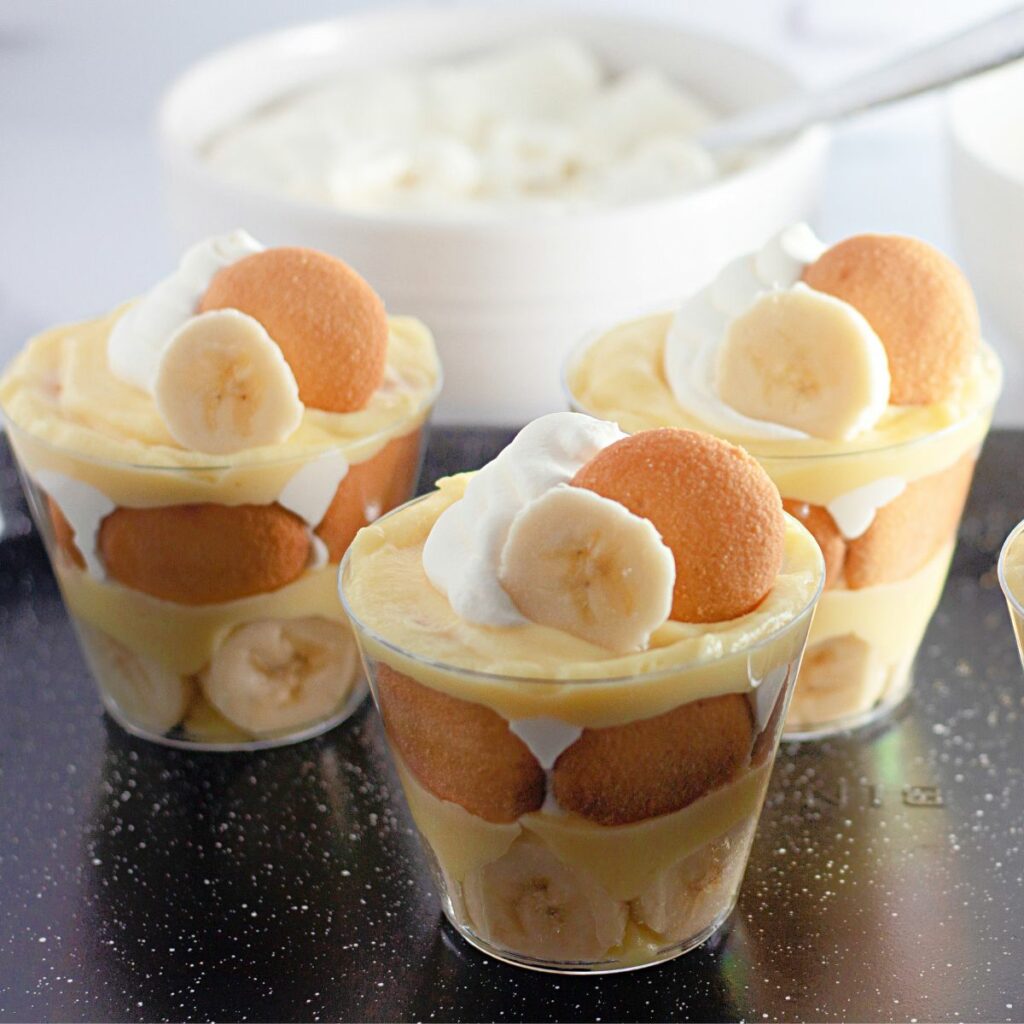 banana pudding cups on black tray.