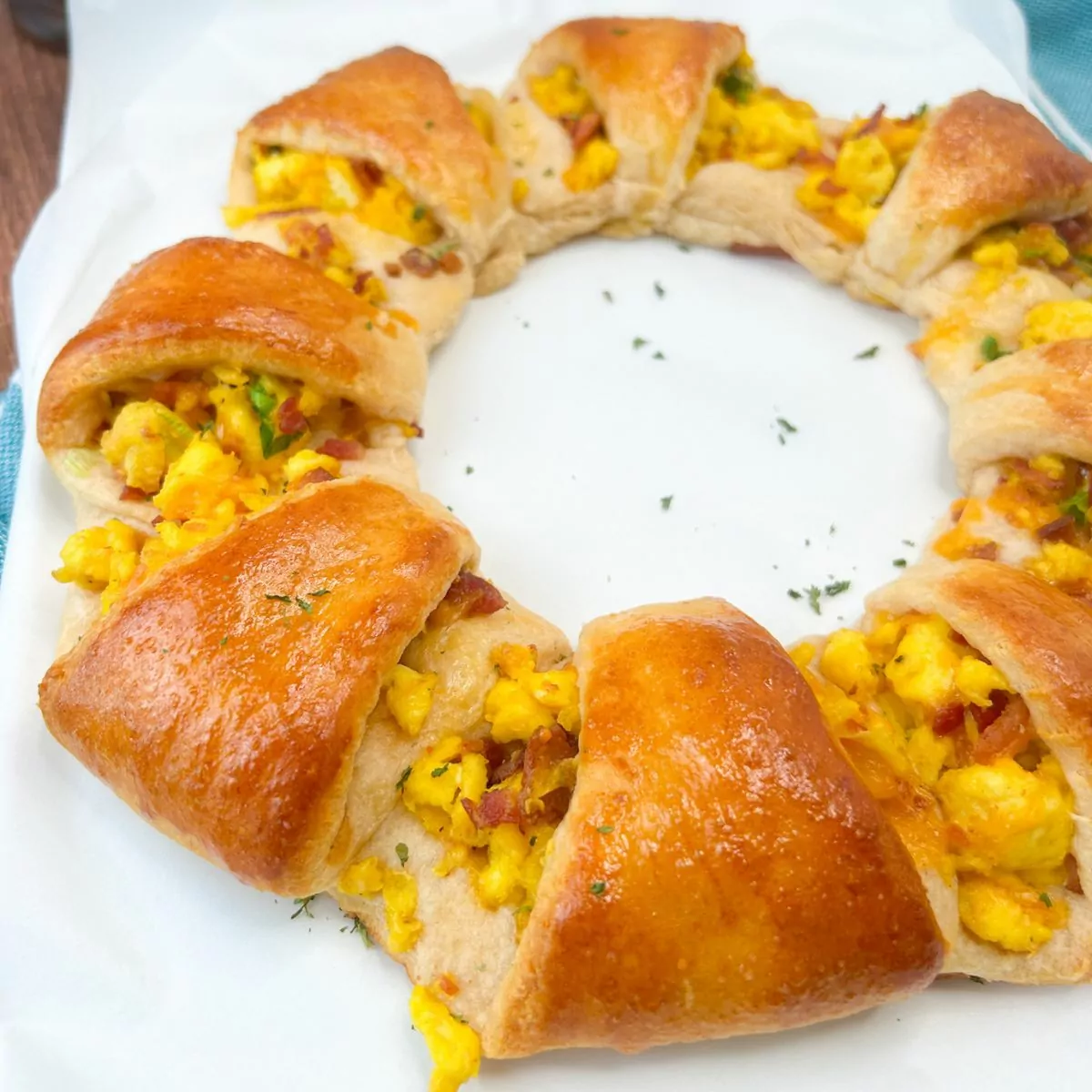 square photo of baked crescent roll wreath with eggs.