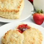 Heart shaped biscuits for Valentine's Day on white plate with fresh strawberries and jam.