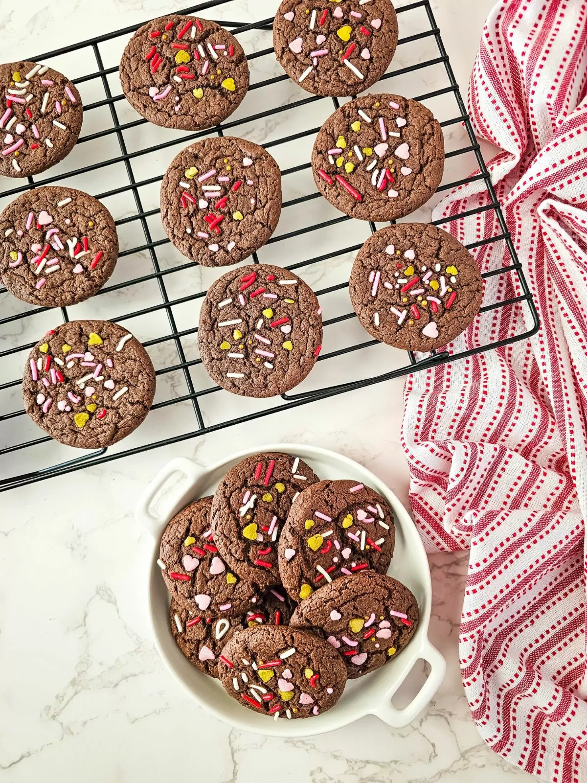 Chocolate cake mix cookies with Valentine's Day sprinkles in bowl and cooling rack.