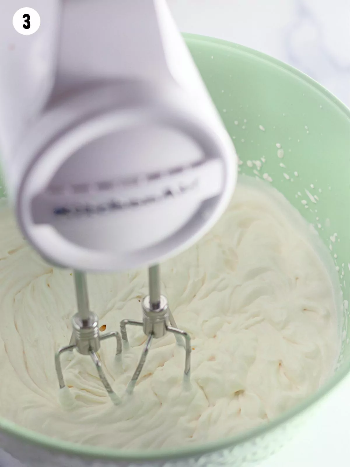 Making homemade whipped cream with electric mixer in bowl.