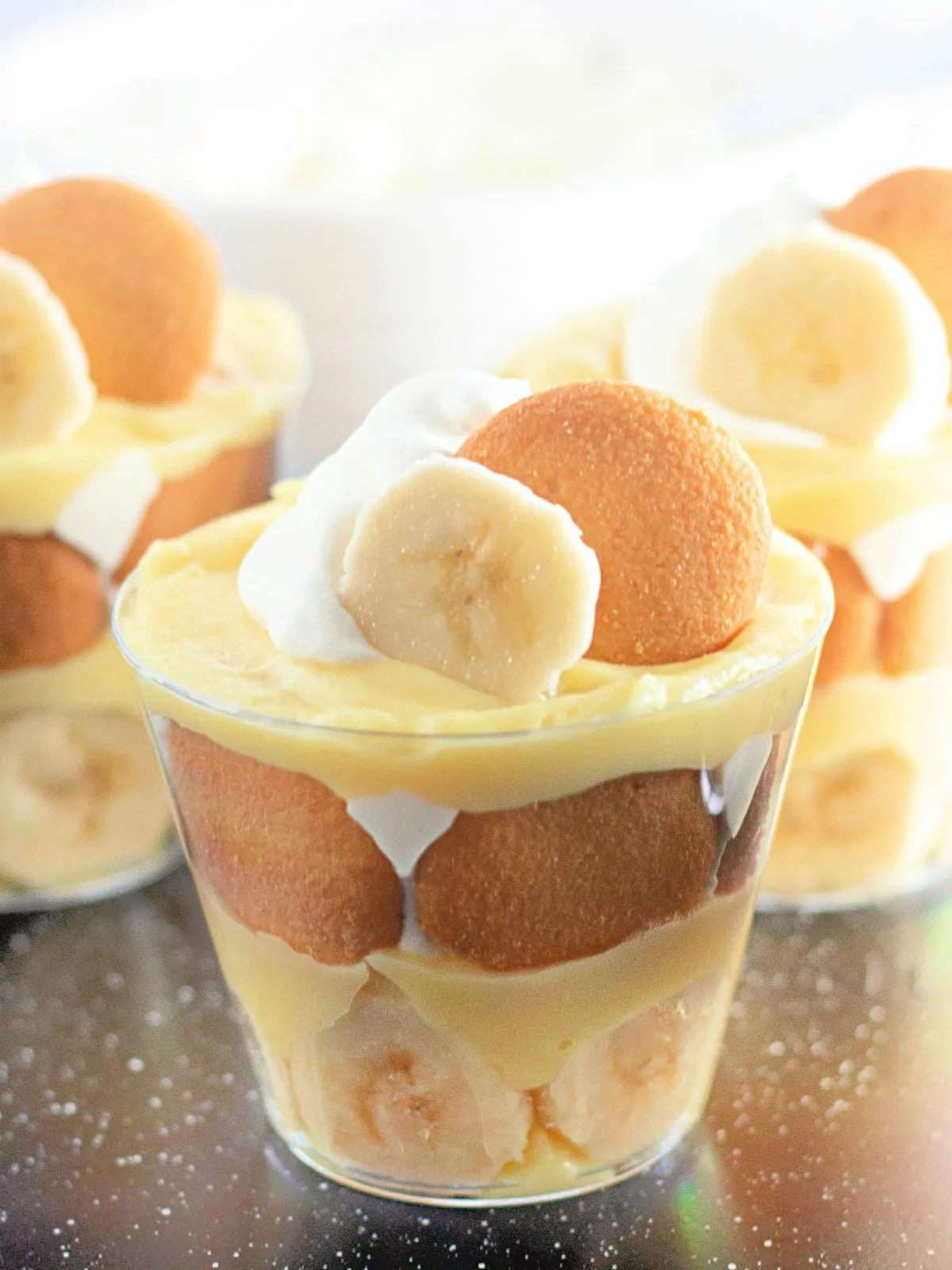 Banana pudding cups topped with sliced bananas and whipped cream.