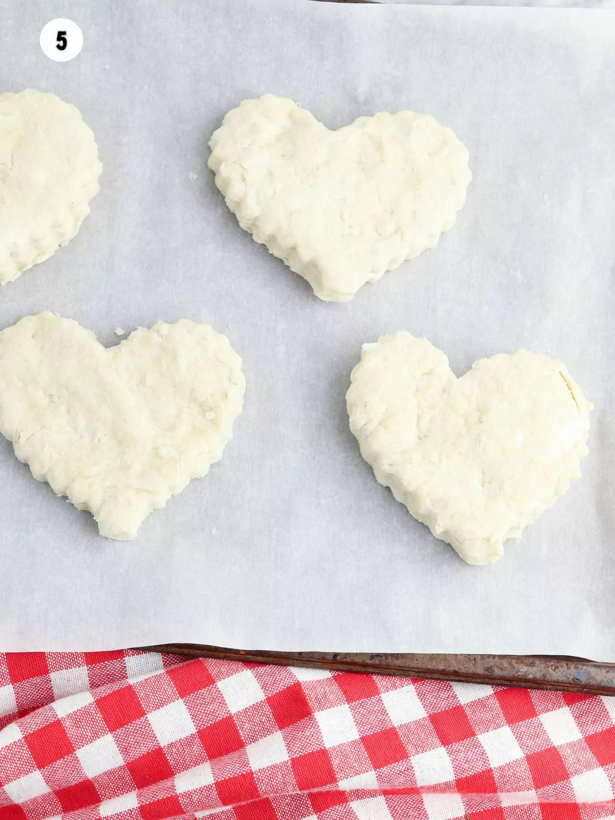 heart shaped biscuits on parchment lined baking sheet.