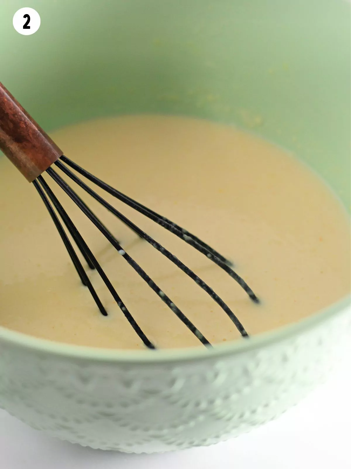vanilla pudding in bowl with wire whisk.