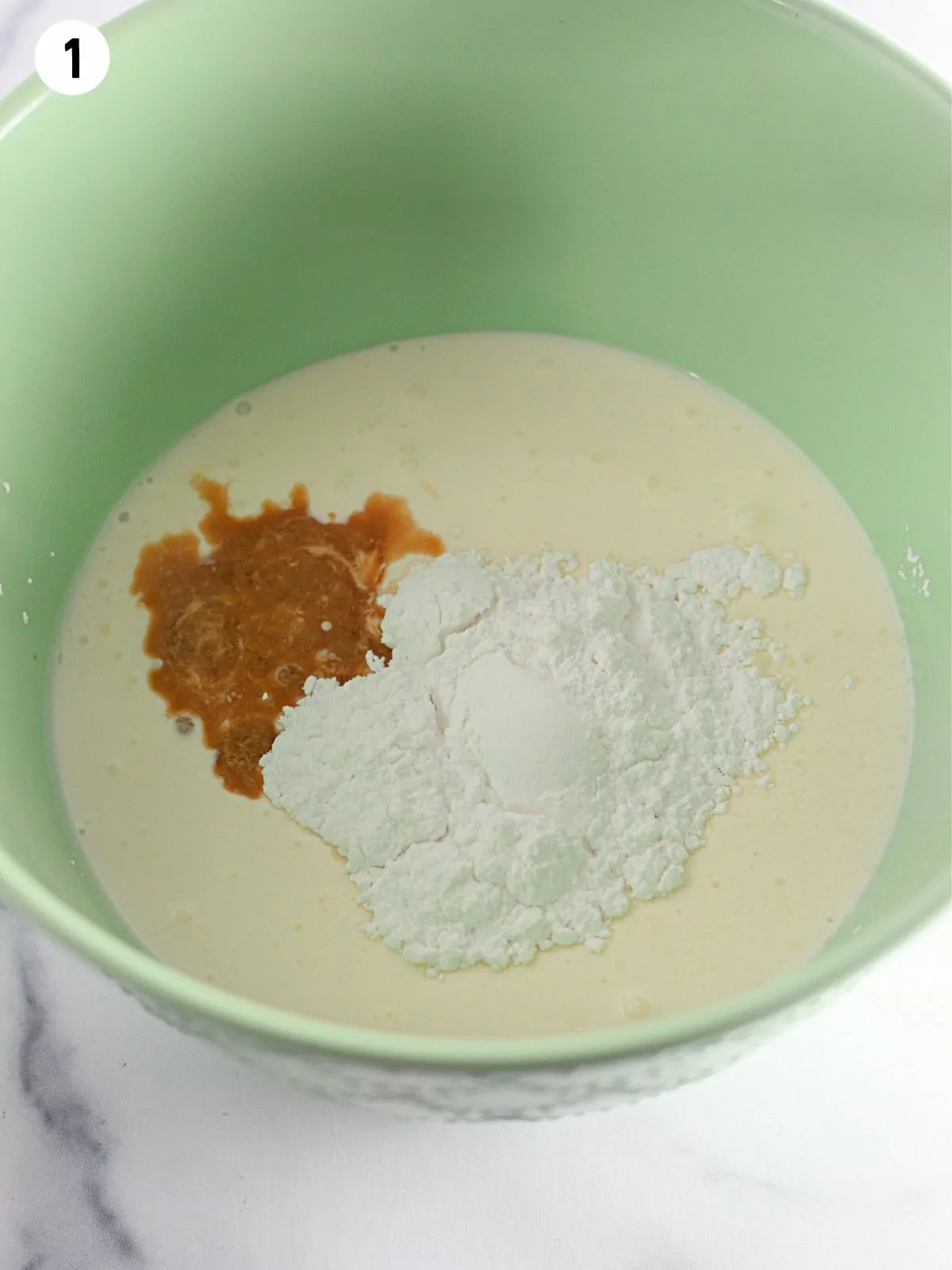 Pudding mix with milk and vanilla extract in bowl.