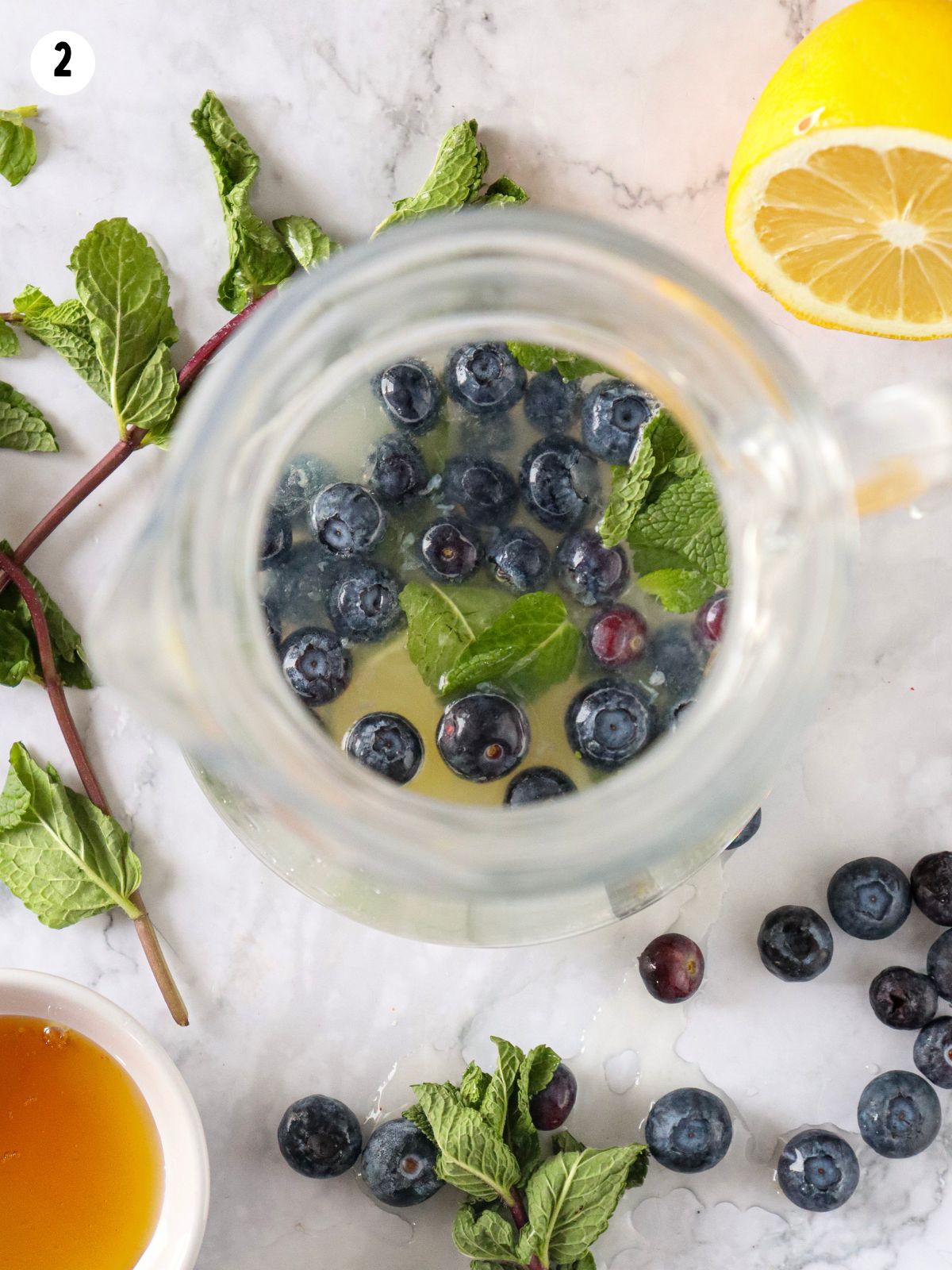 overhead view of blueberries in pitcher with mint leaves.