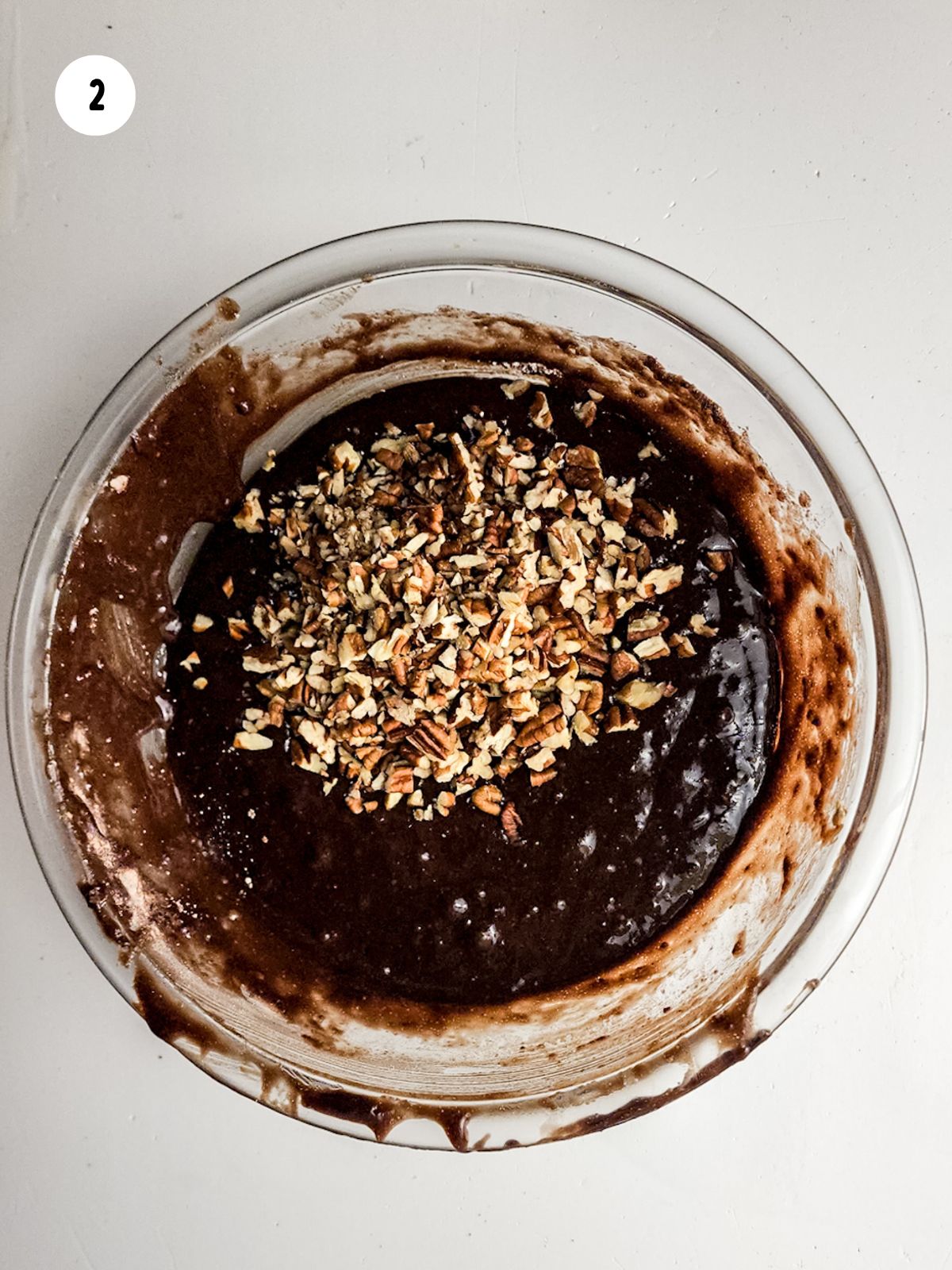 brownie batter in bowl with crushed pecans.