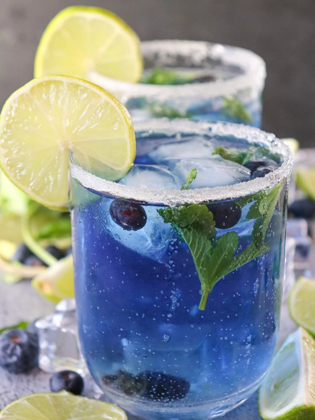 closeup of blueberry mocktail with mint leaves and lime slices.