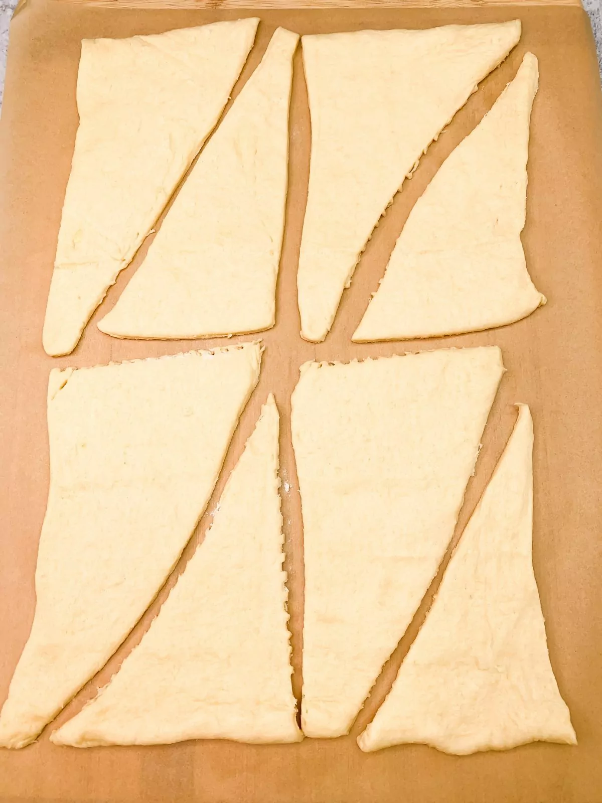 crescent rolls laid out on parchment paper.