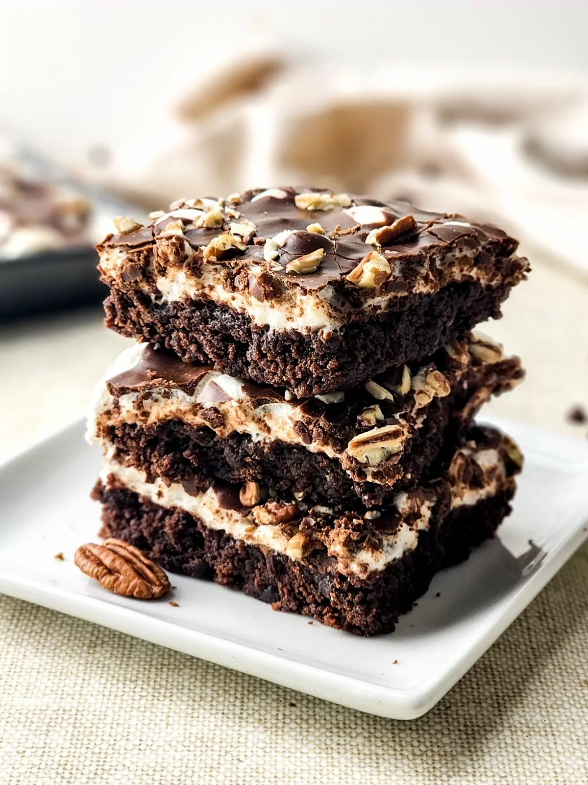 baked brownies with marshmallows stacked on white plate.