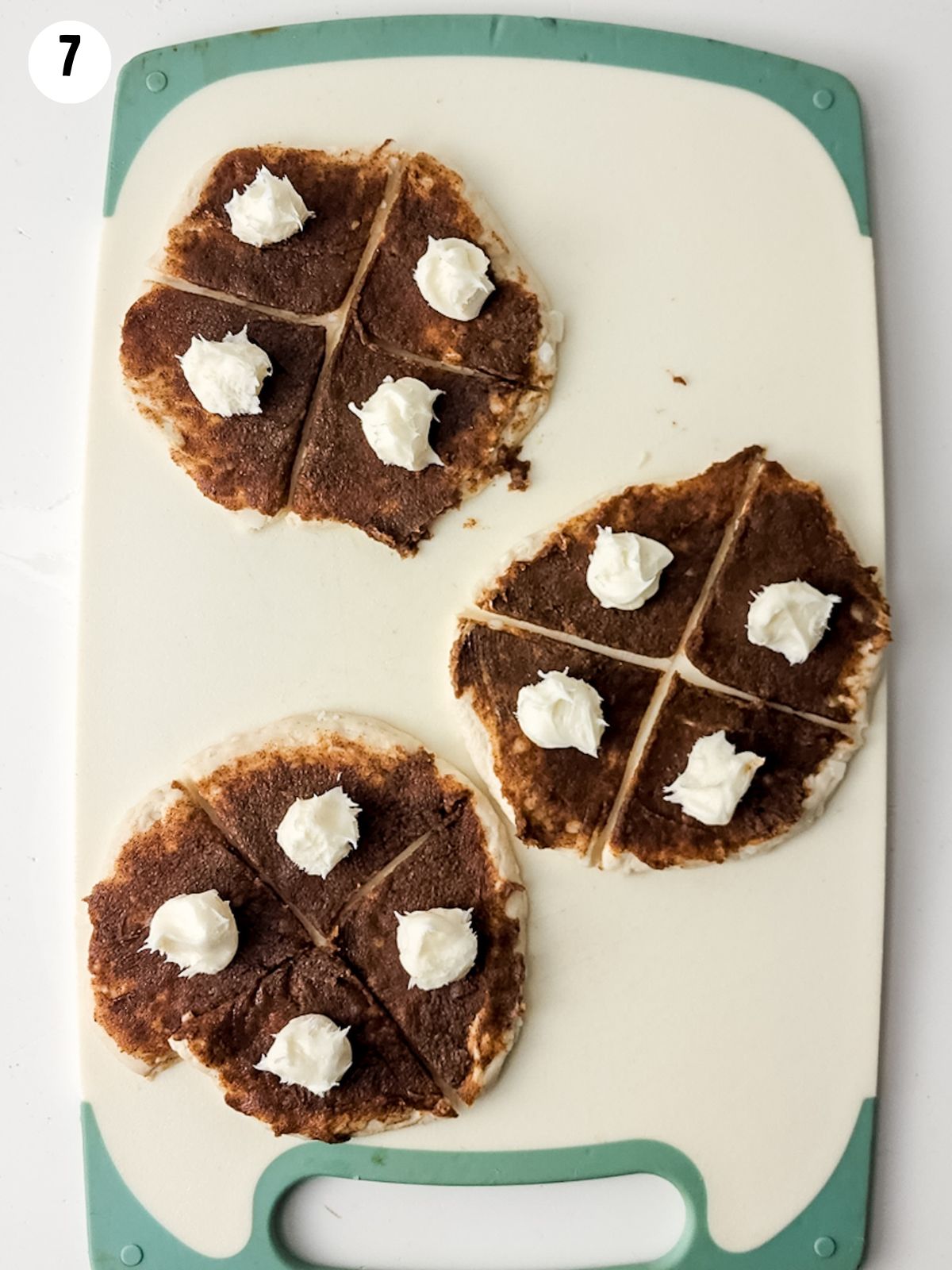 dollops of cream cheese frosting on refrigerator biscuits spread with cinnamon roll mixture.