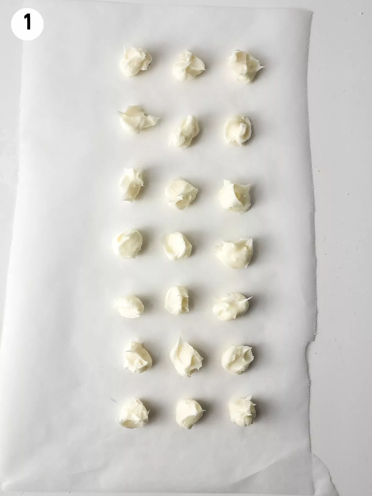 dollops of cream cheese frosting on parchment paper.