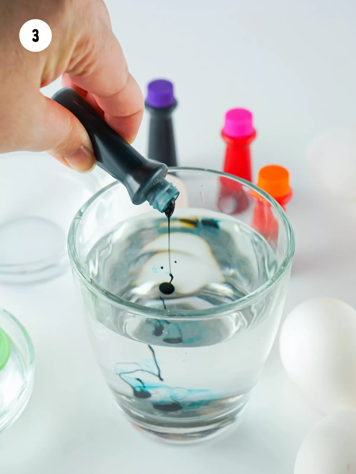 adding drops of blue food coloring to glass of water.