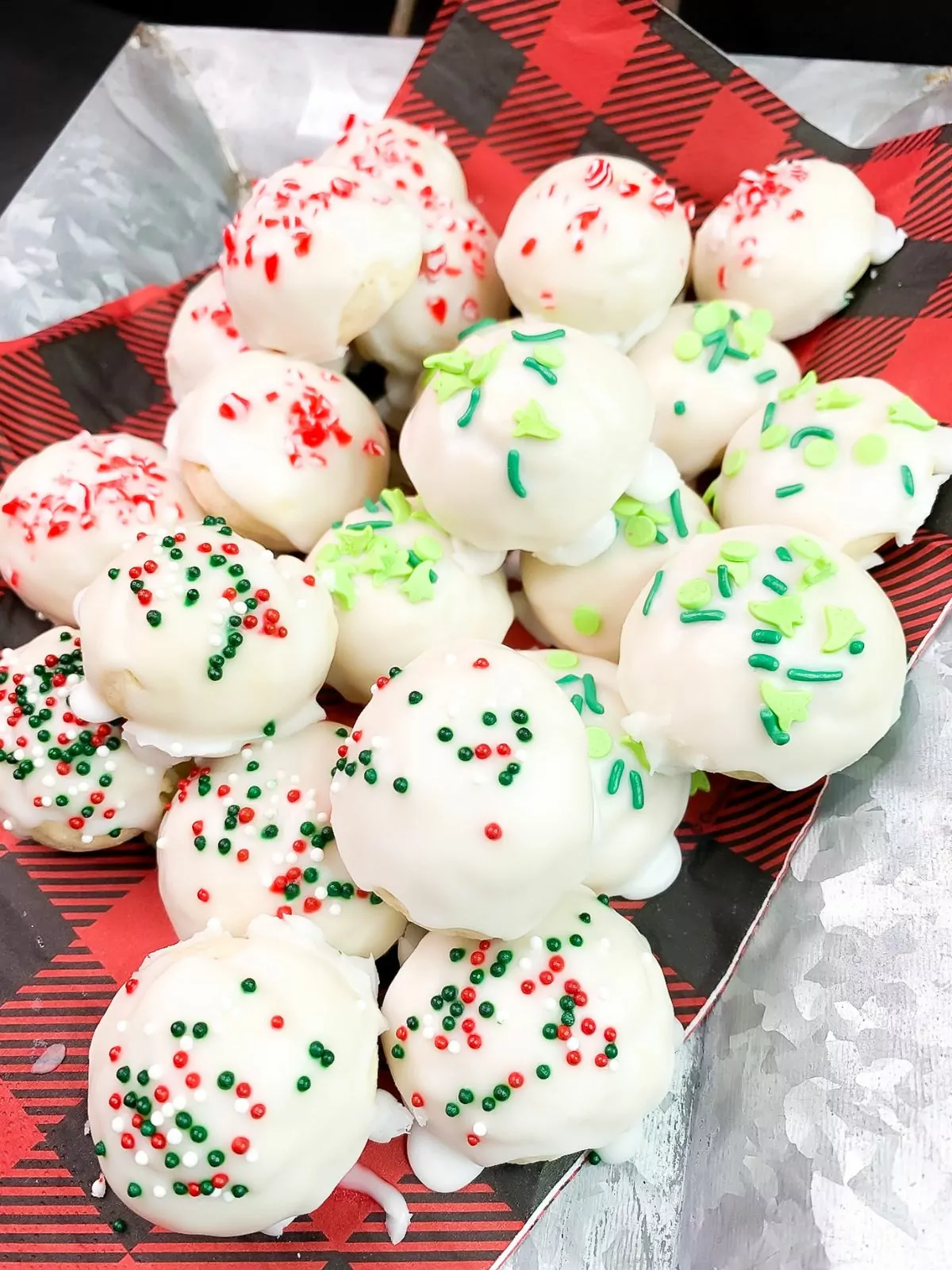 a plate of different colored sprinkle cookies on top of a buffalo plaid napkin.