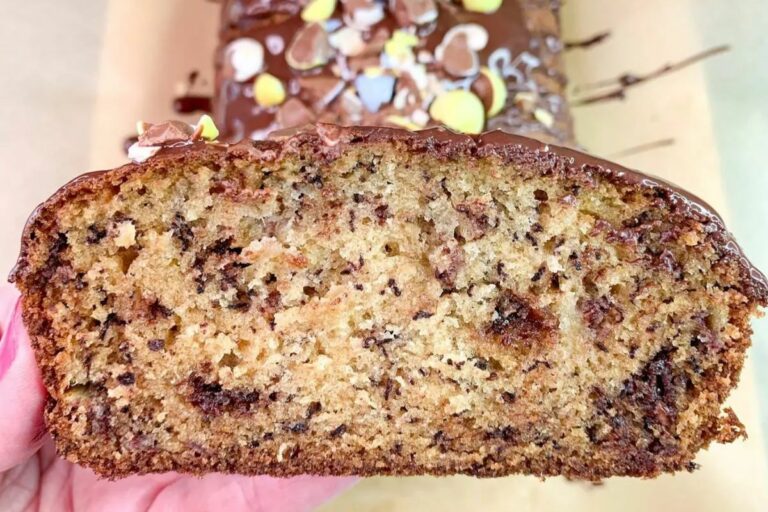 A slice of banana bread with chocolate chips and a chocolate drizzle, topped with colorful candies.