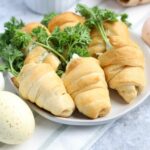 Crescent roll shaped carrots filled with garlic spinach spread and topped with parsley