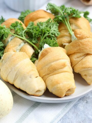 Crescent roll shaped carrots filled with garlic spinach spread and topped with parsley