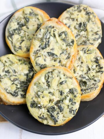 Egg shaped Spinach Artichoke Puff Pastries on a black plate.