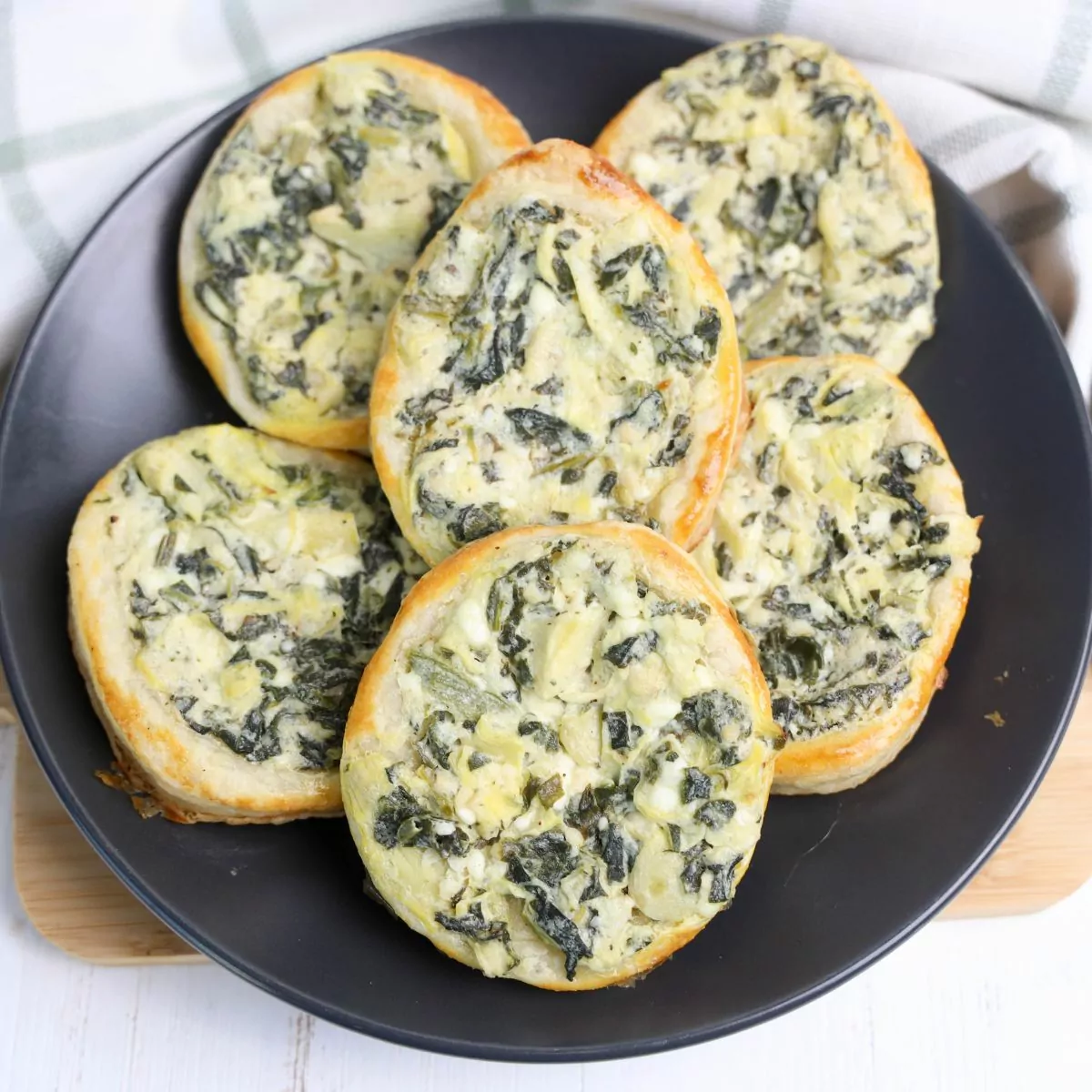 Egg shaped Spinach Artichoke Puff Pastries on a black plate.