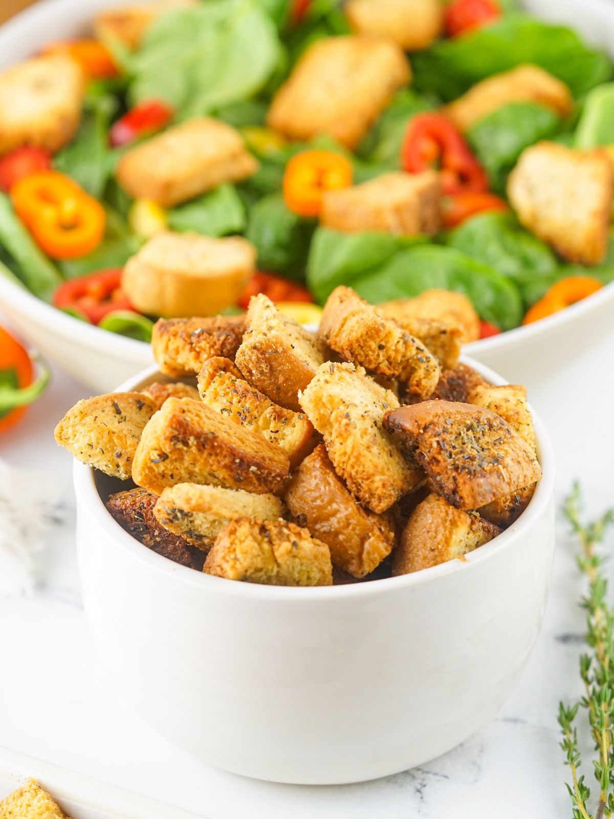 white bowl with homemade croutons with tossed salad in background.
