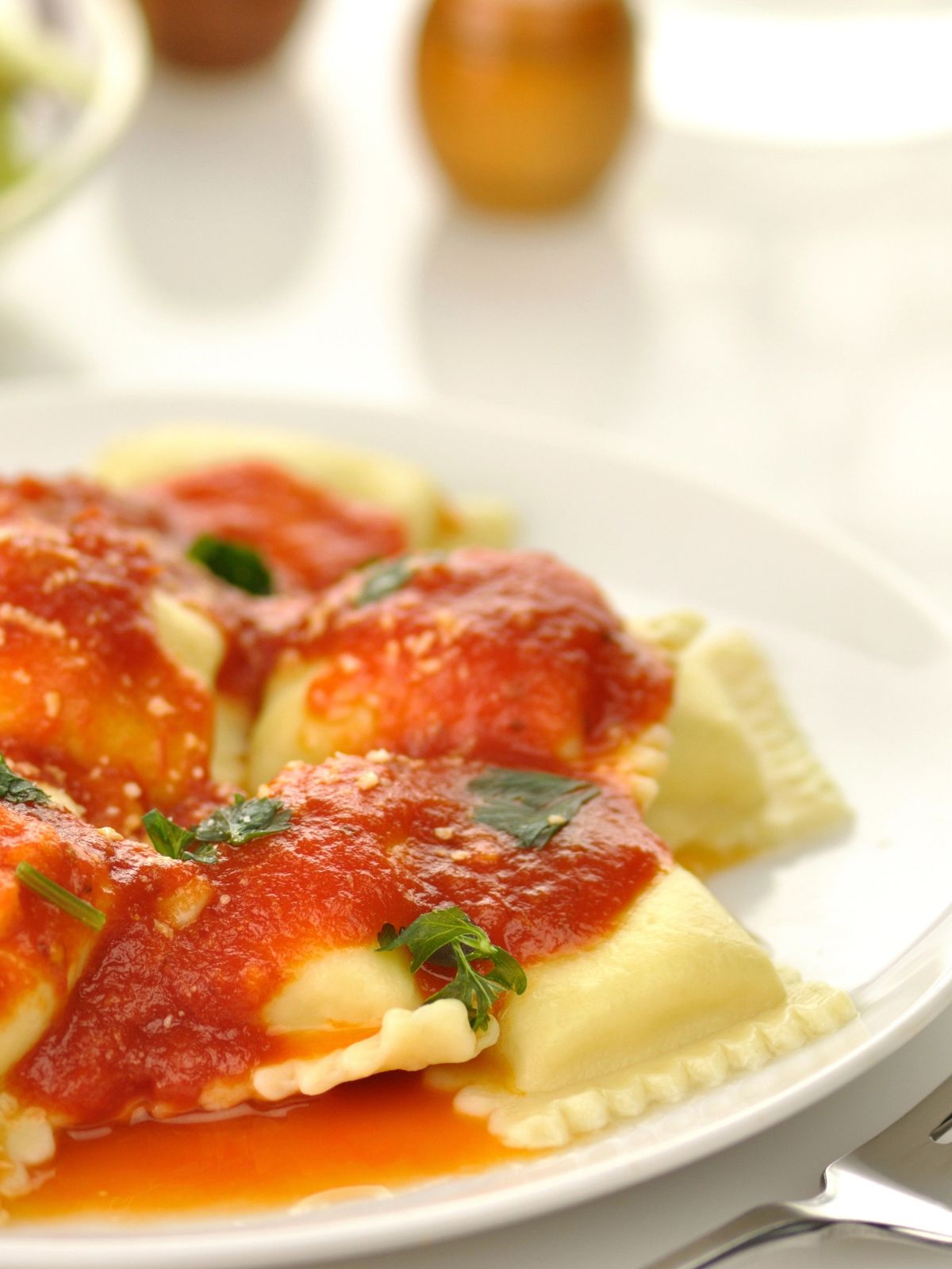 homemade square pasta on plate with tomato sauce and basil.